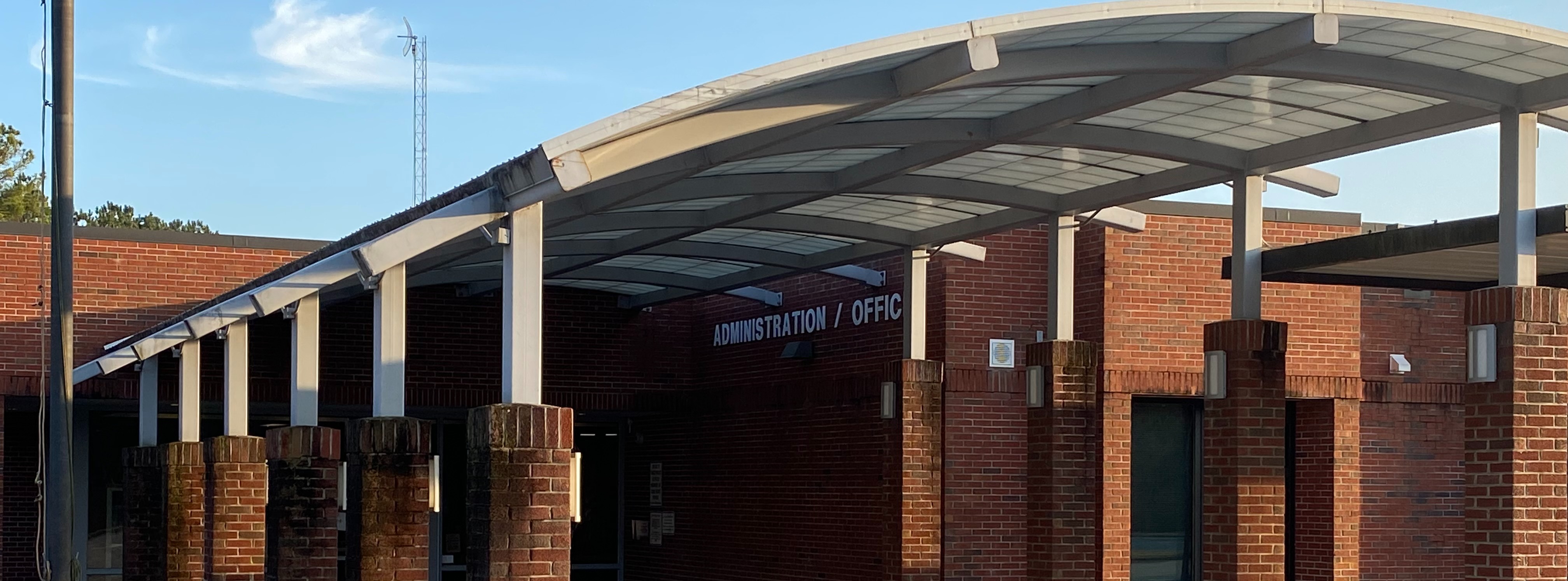 Exterior view of Liberty Middle School showing the brick building entrance with a covered arched walkway leading to the administration offices.