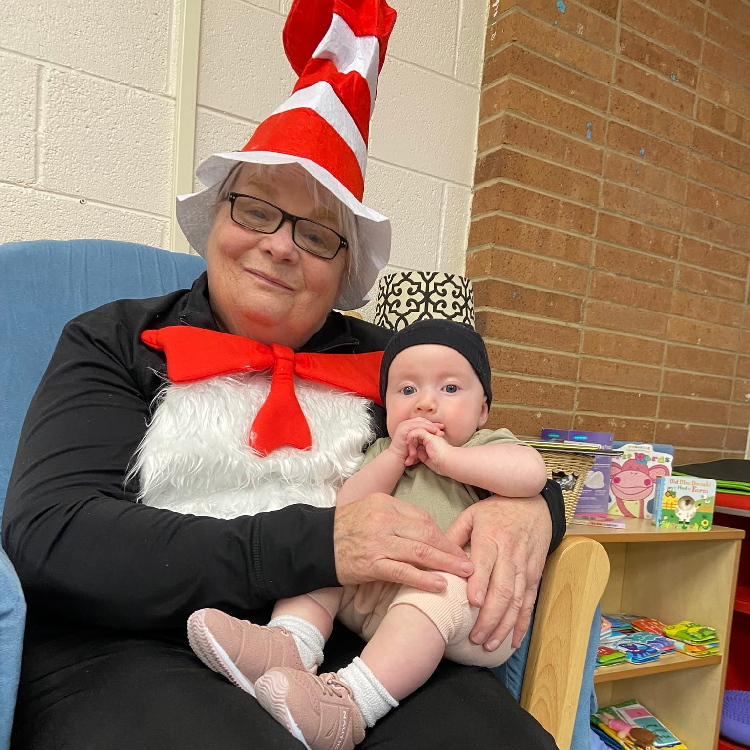 Teacher dressed up like Dr. Seuss holding a Birth to 3 baby