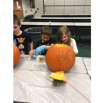 2 students cleaning a pumpkin together