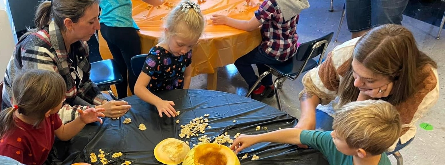 Teacher engages with students and carves pumpkins