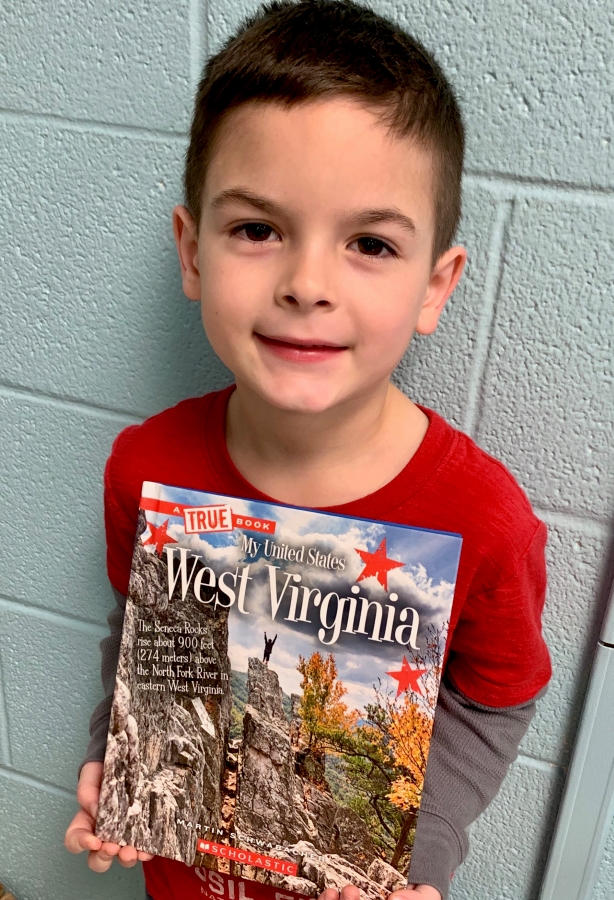 Student holding up a book of West Virginia