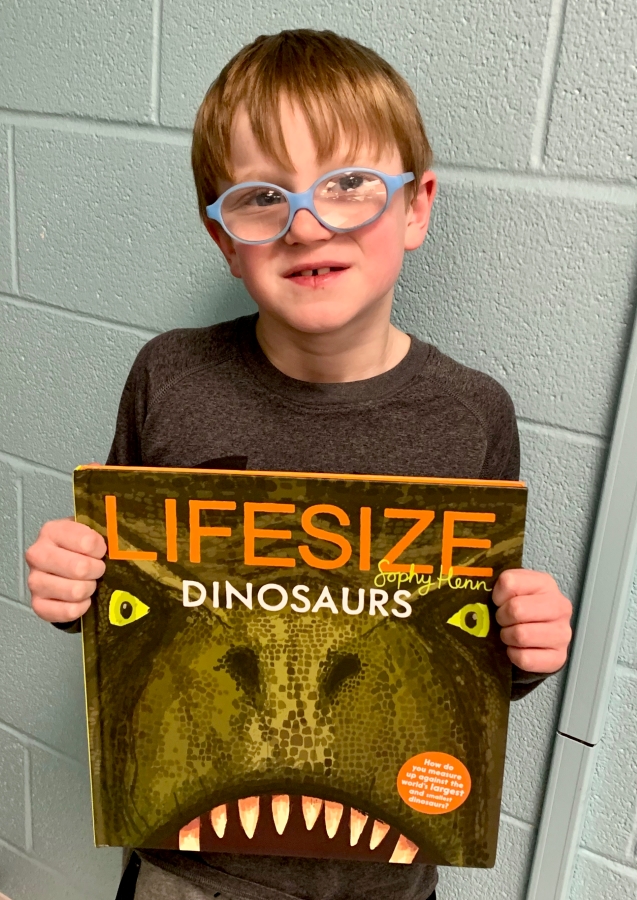 Student holding up a dinosaur book