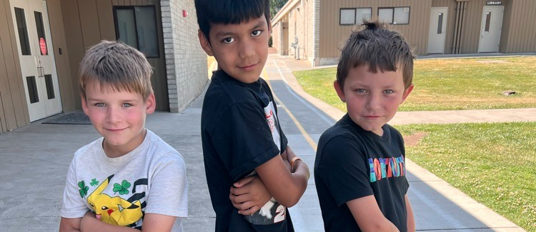 three boys standing on sidewalk