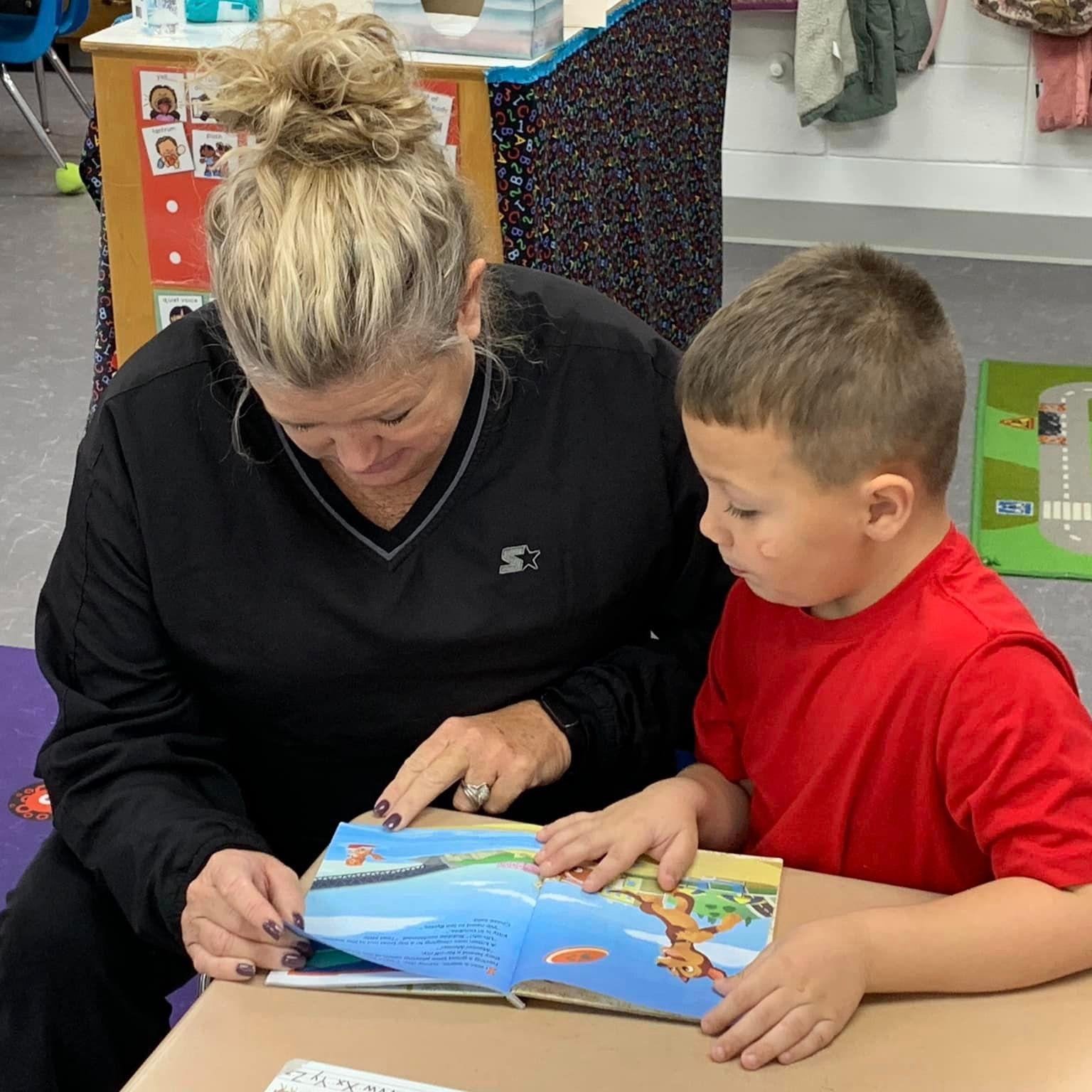 teacher helping student read book