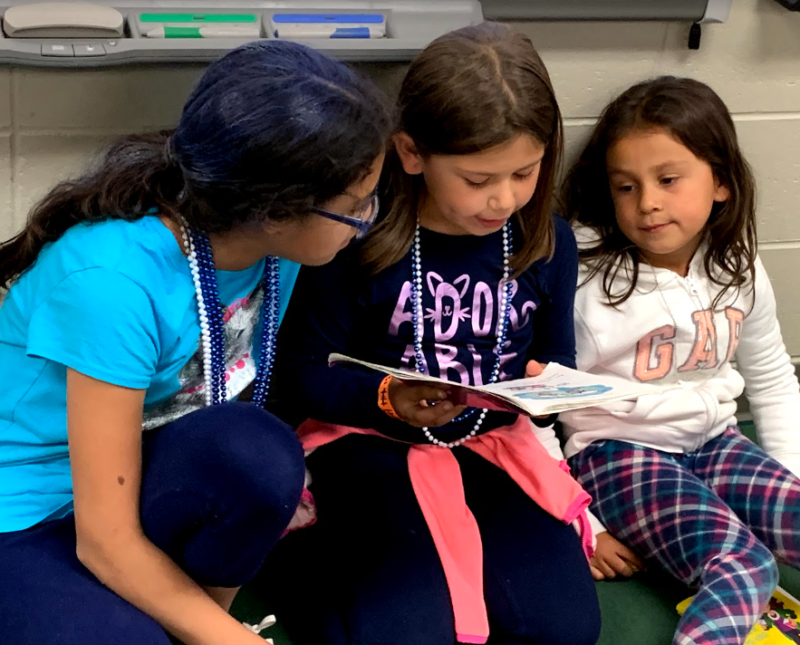 Three girls reading a book