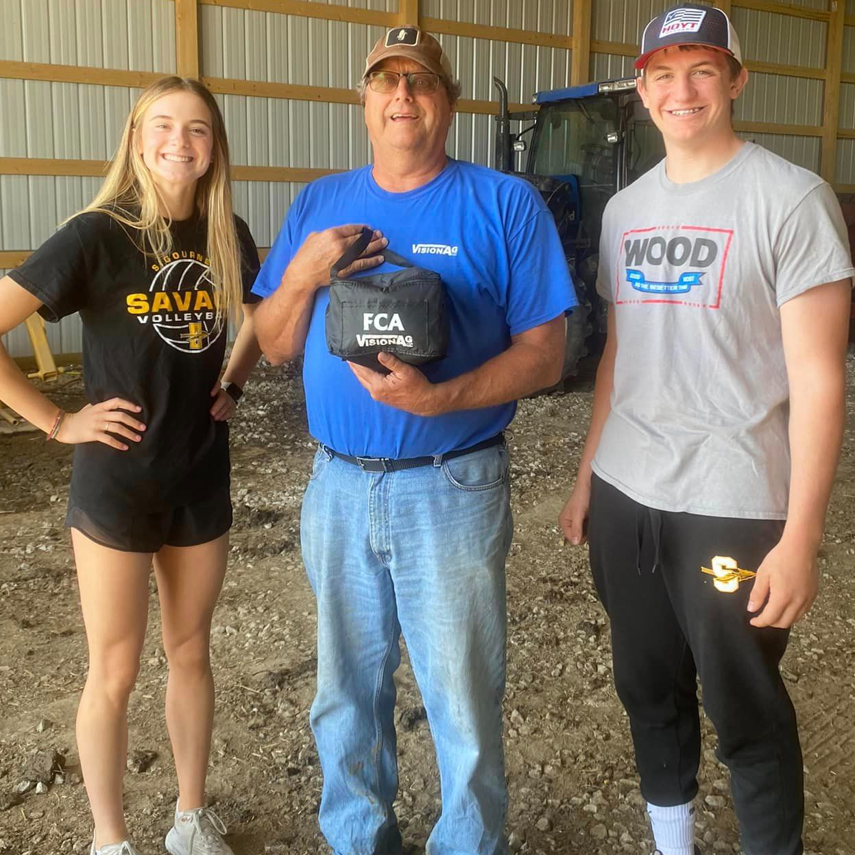 two students pose with farmer