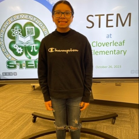 girl in dark long sleeve shirt in front of a projector with Cloverleaf Elementary STEM logo