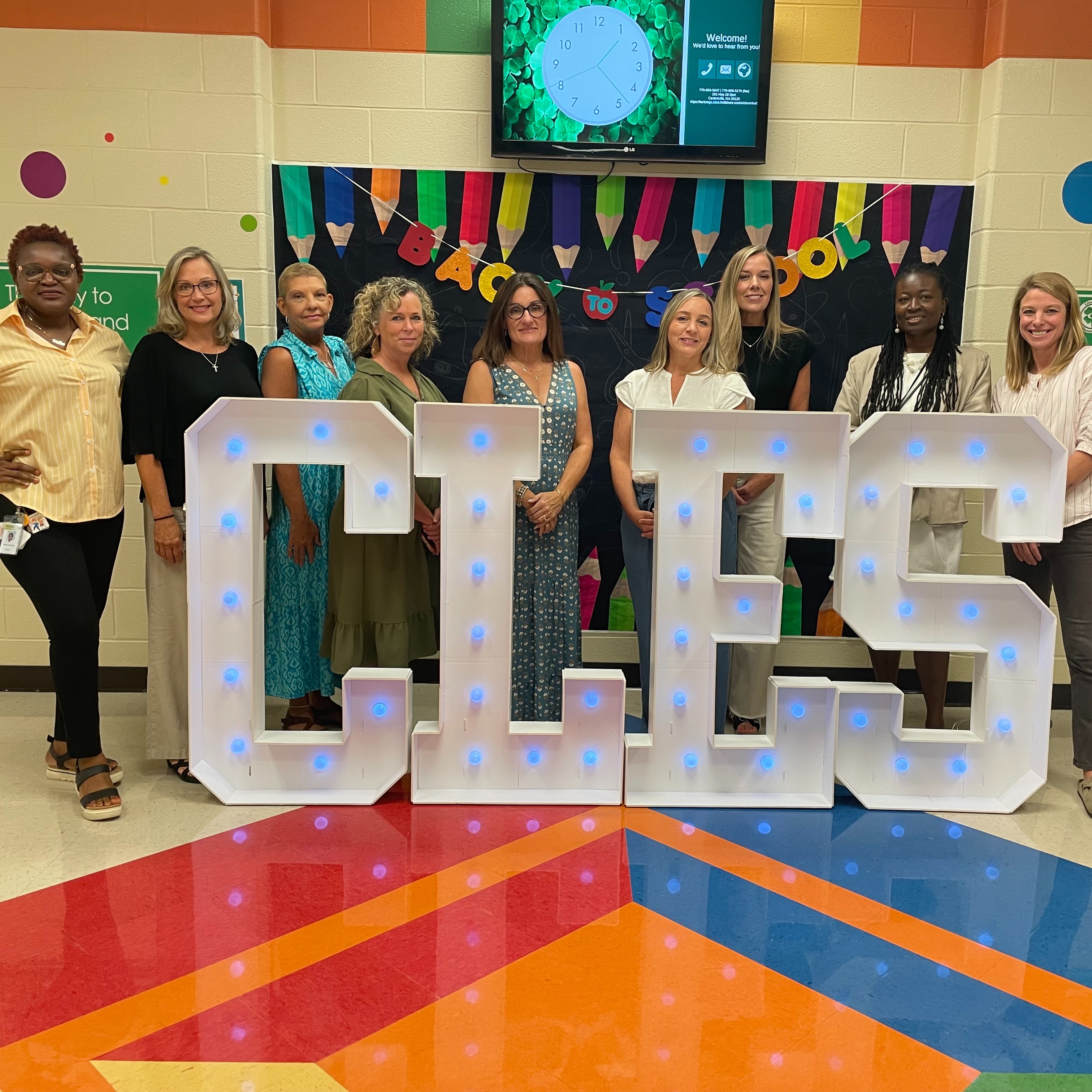 Nine smiling female educators facing the camera at a Back to School display