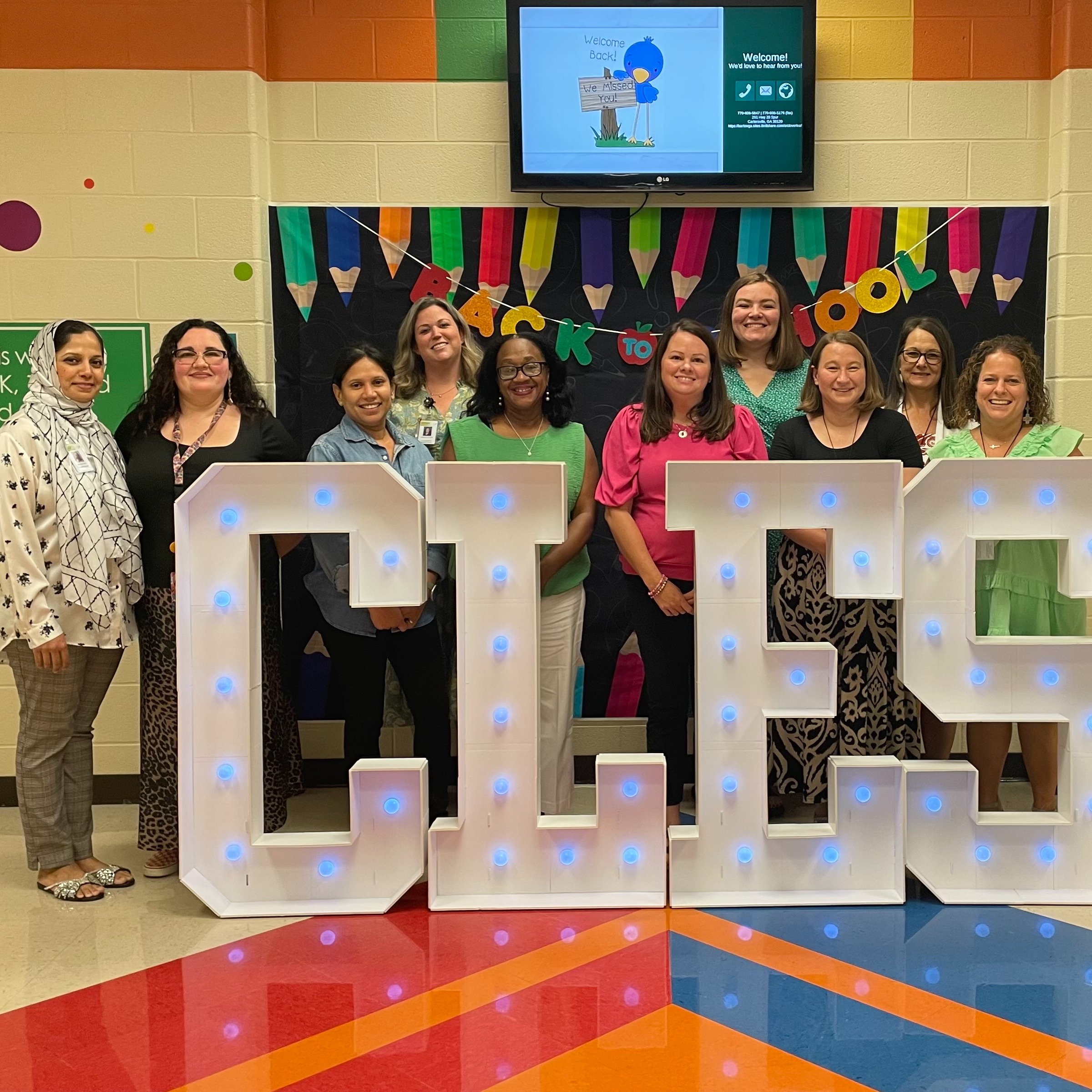 10 smiling female educators facing the camera in front of a back to school display