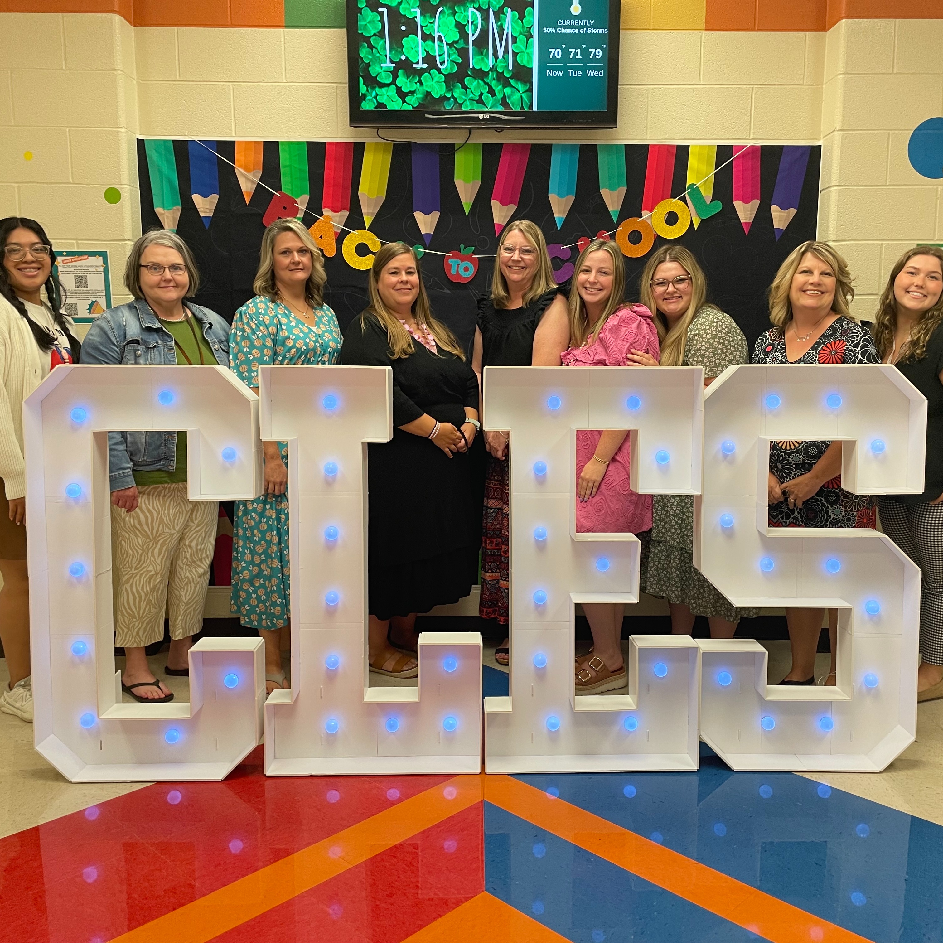 Nine smiling female educators facing the camera at a Back to School display