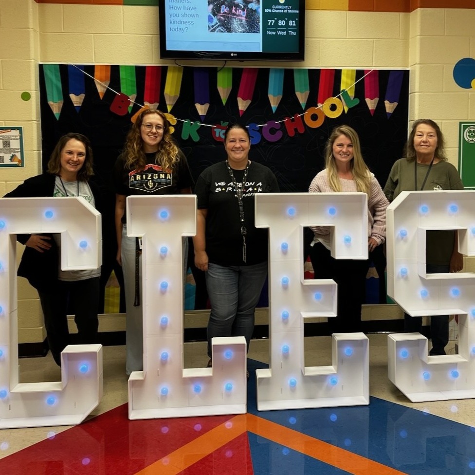 Five smiling female educators posing for a photo at the Back to School display