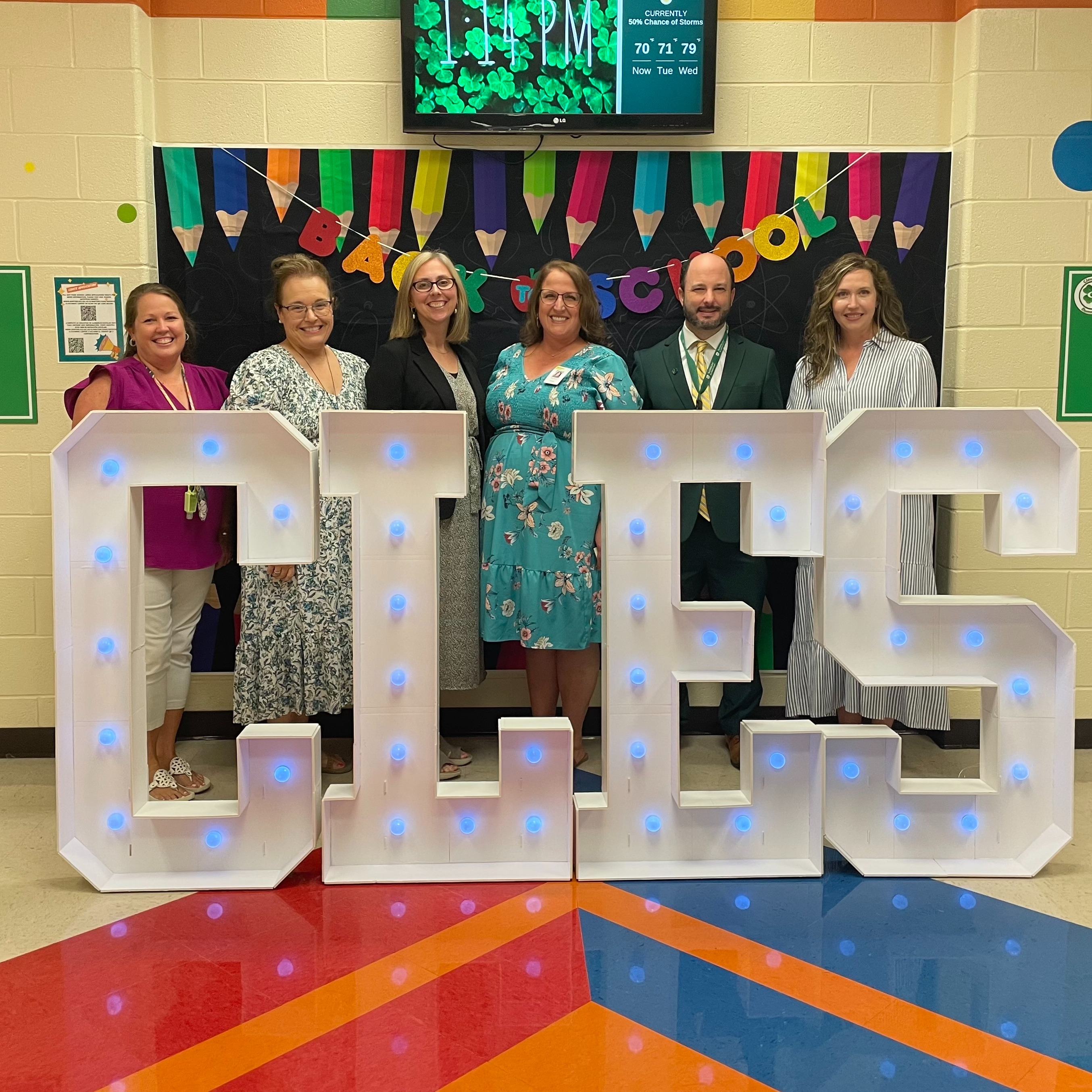 Five educators smiling for a photo at the Back to School set up