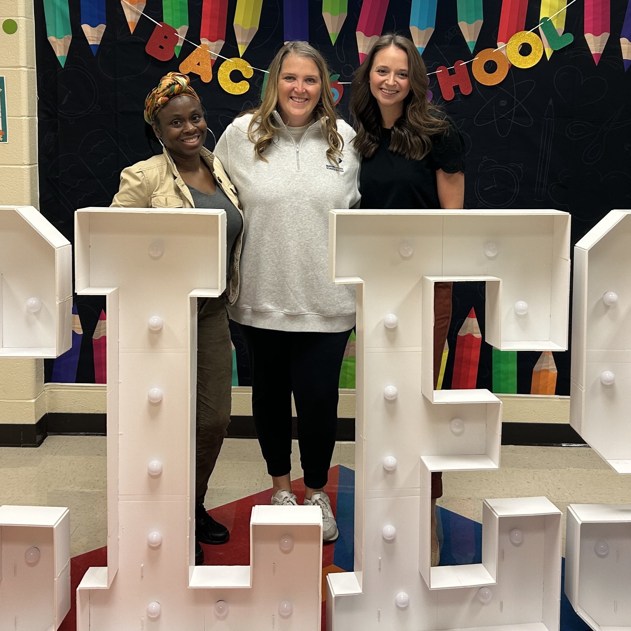 three smiling educators posing for a photo at the back to school display