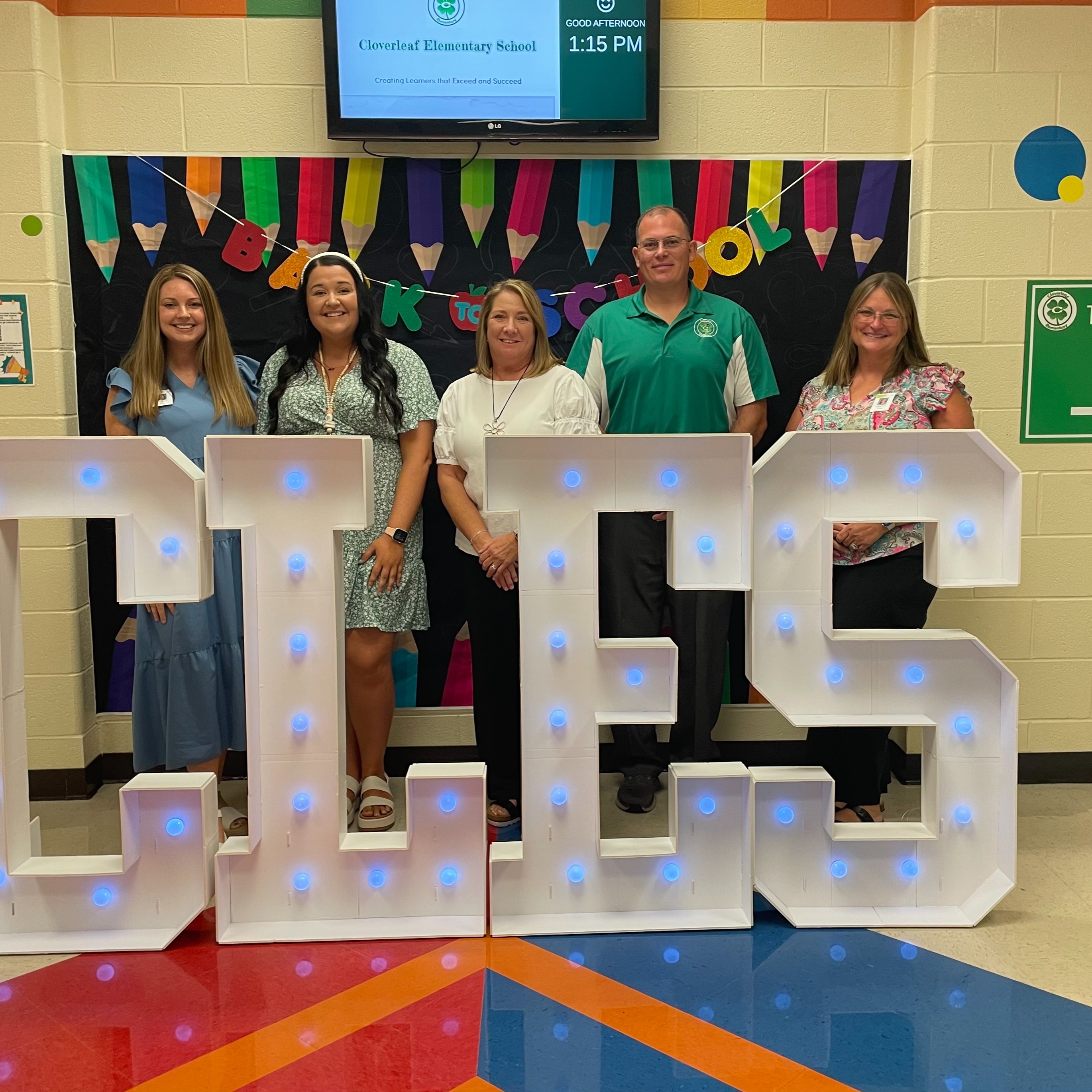 Five smiling educators posing for a photo at the Back to School display