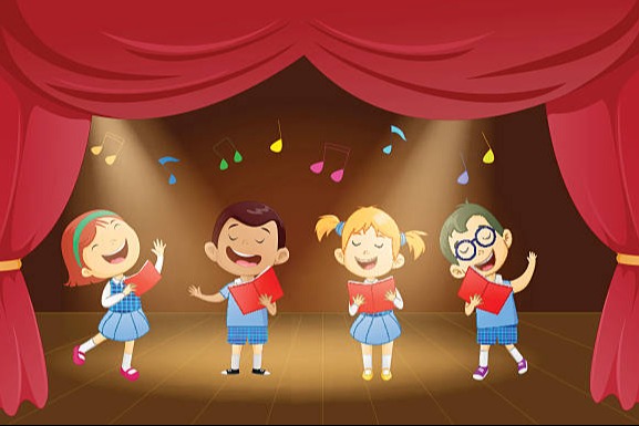 Four children dressed in blue uniforms are on a stage holding red books and singing.