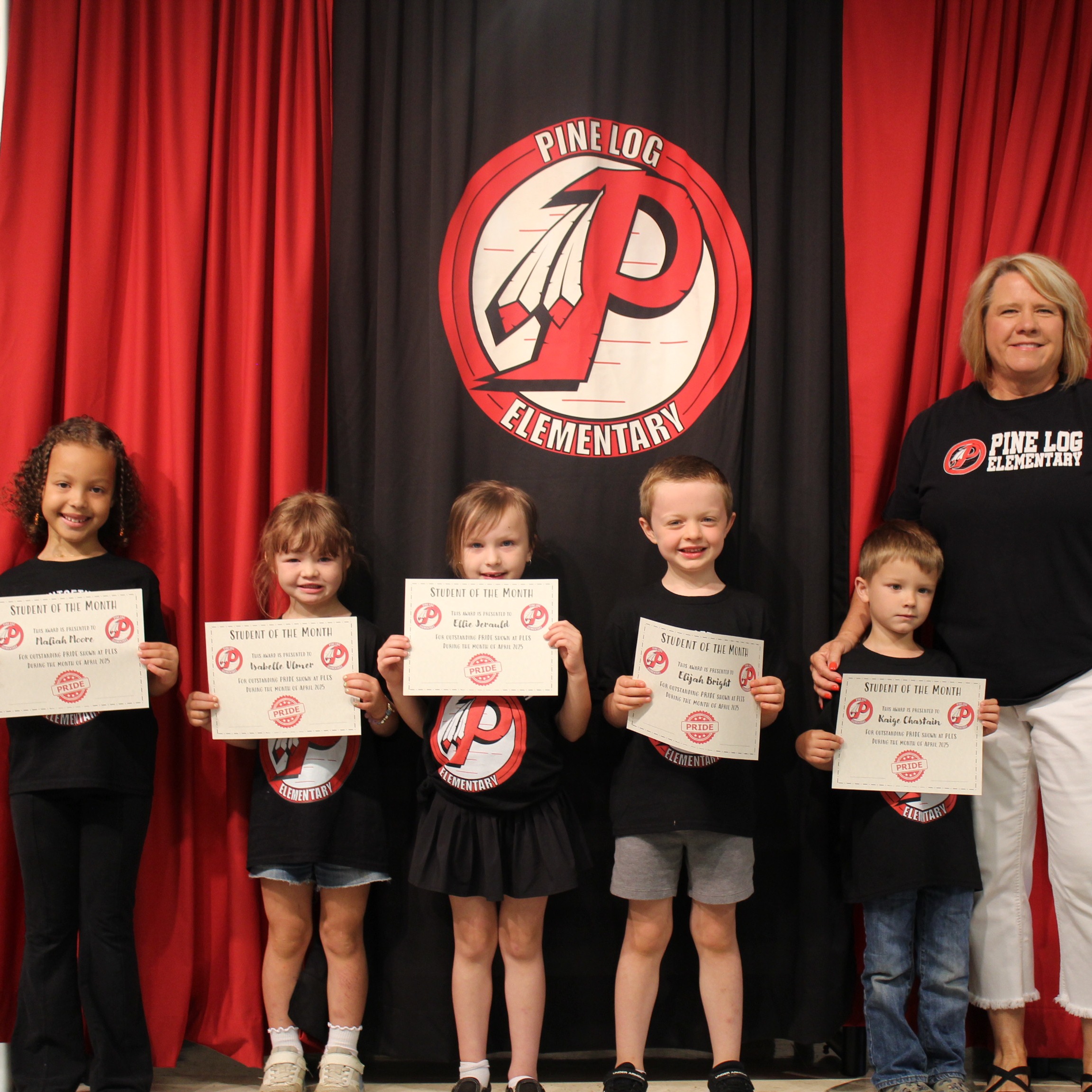 One adult and 5 children  standing on stage holding awards for student of the month.