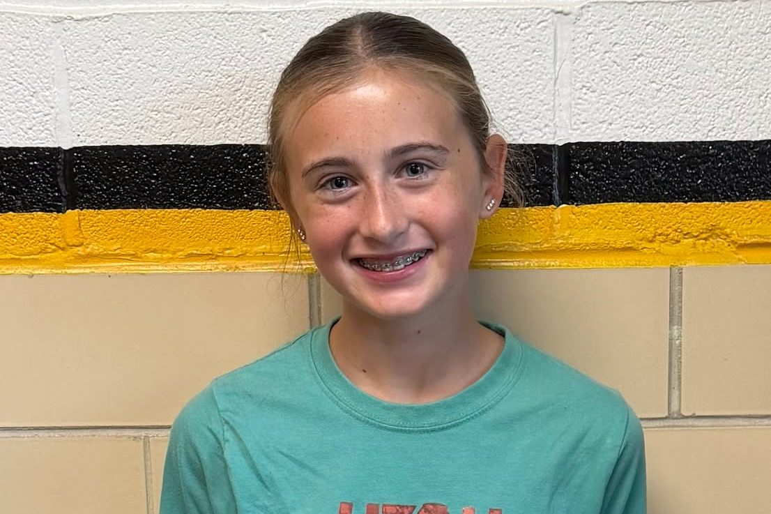 Jr./Sr. High Student of the Week posed for a portrait against a school hallway wall with black and gold accent stripes.