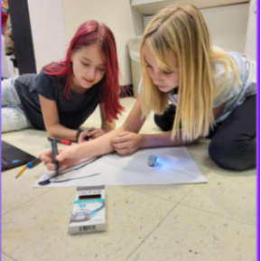 2  girls coding an  ozobot