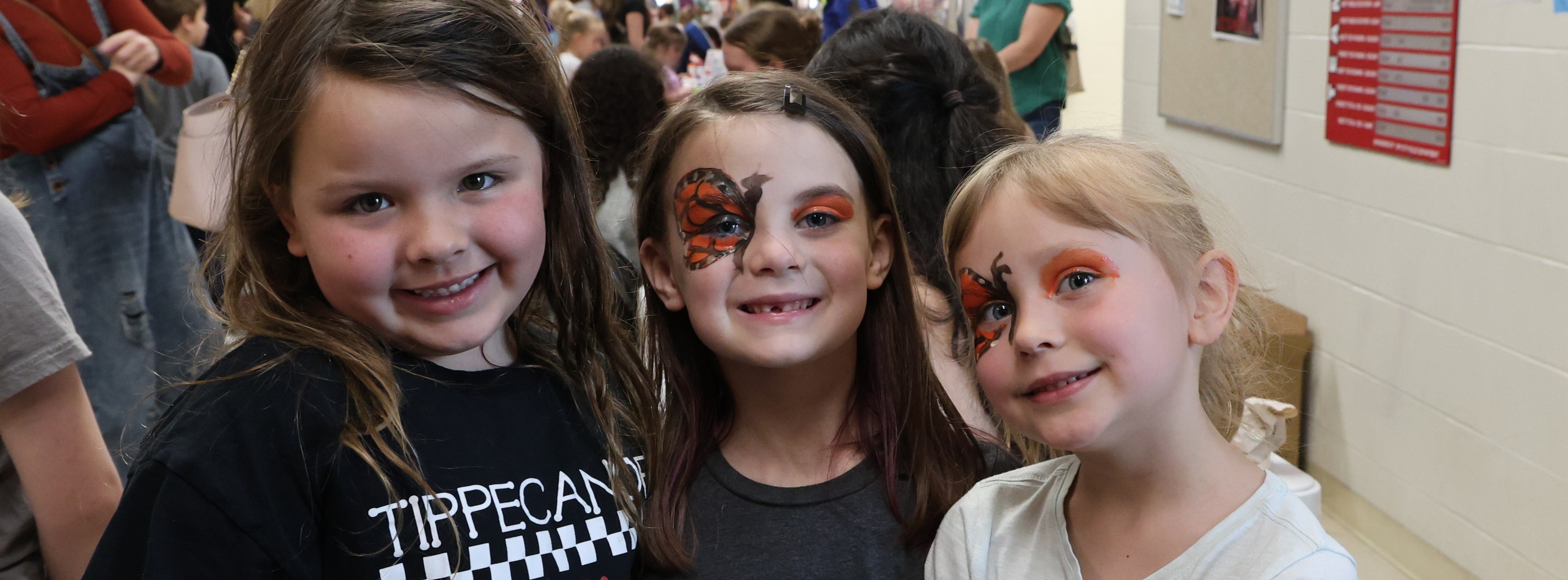 Three elementary students show off their face painting at Elevate the Arts.