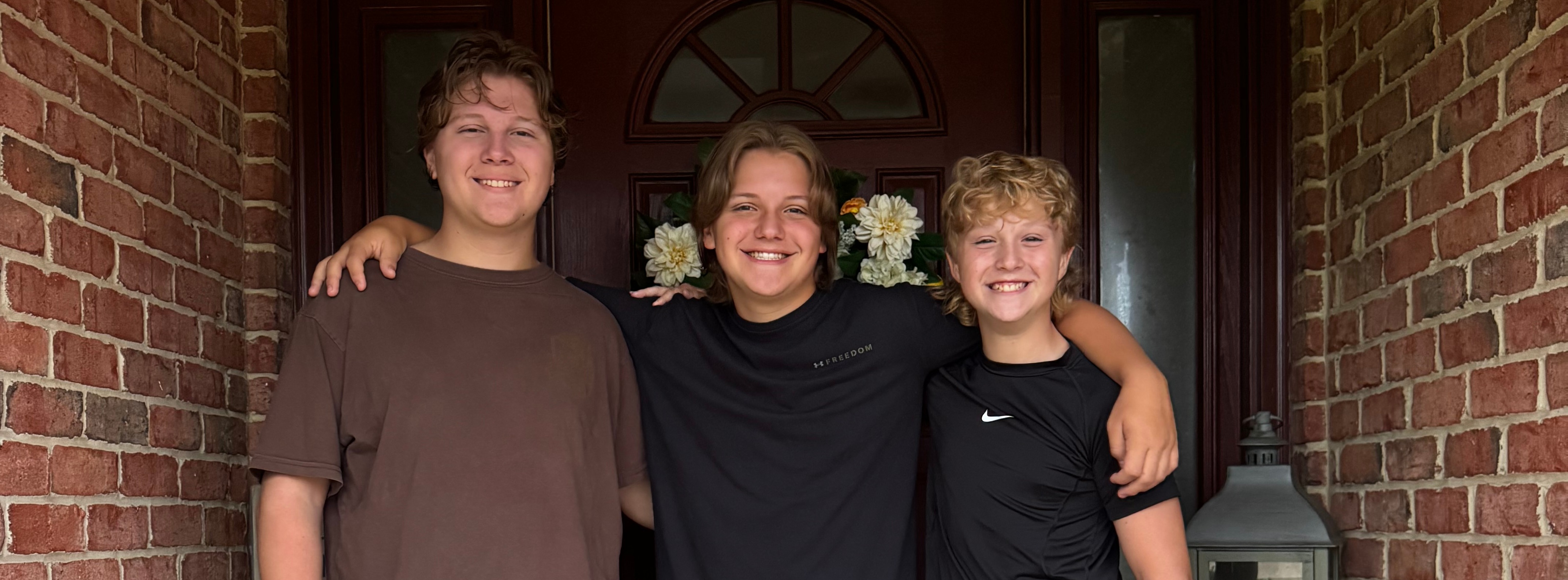Three teenagers pose together on the front porch on the first day of school.