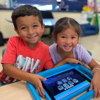 Image of elementary children smiling and playing with IPAD
