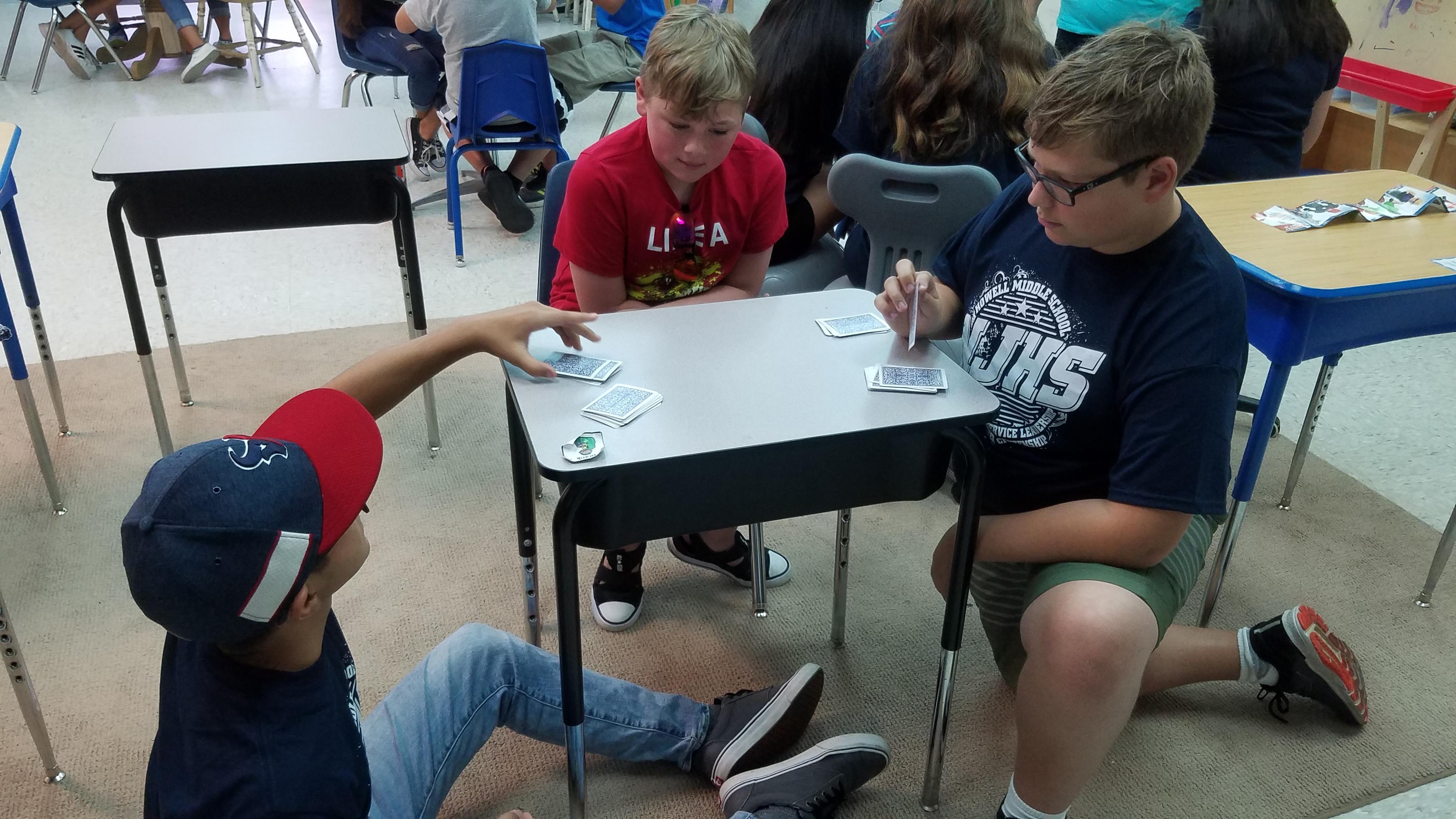 Student playing cards with 2 students
