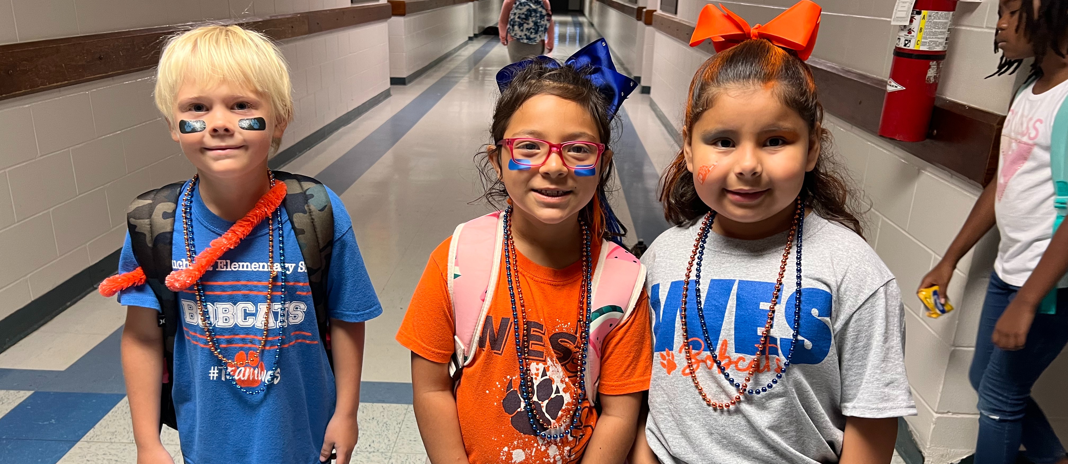 three children dressed in blue and orange for spirit day