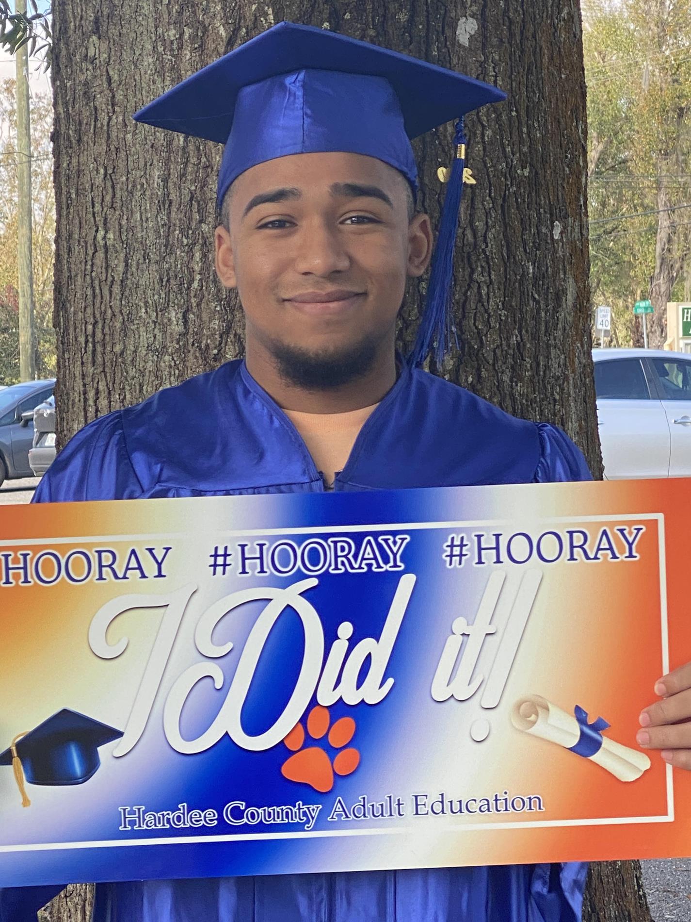 Adult graduate holding a sign that says "I did it"