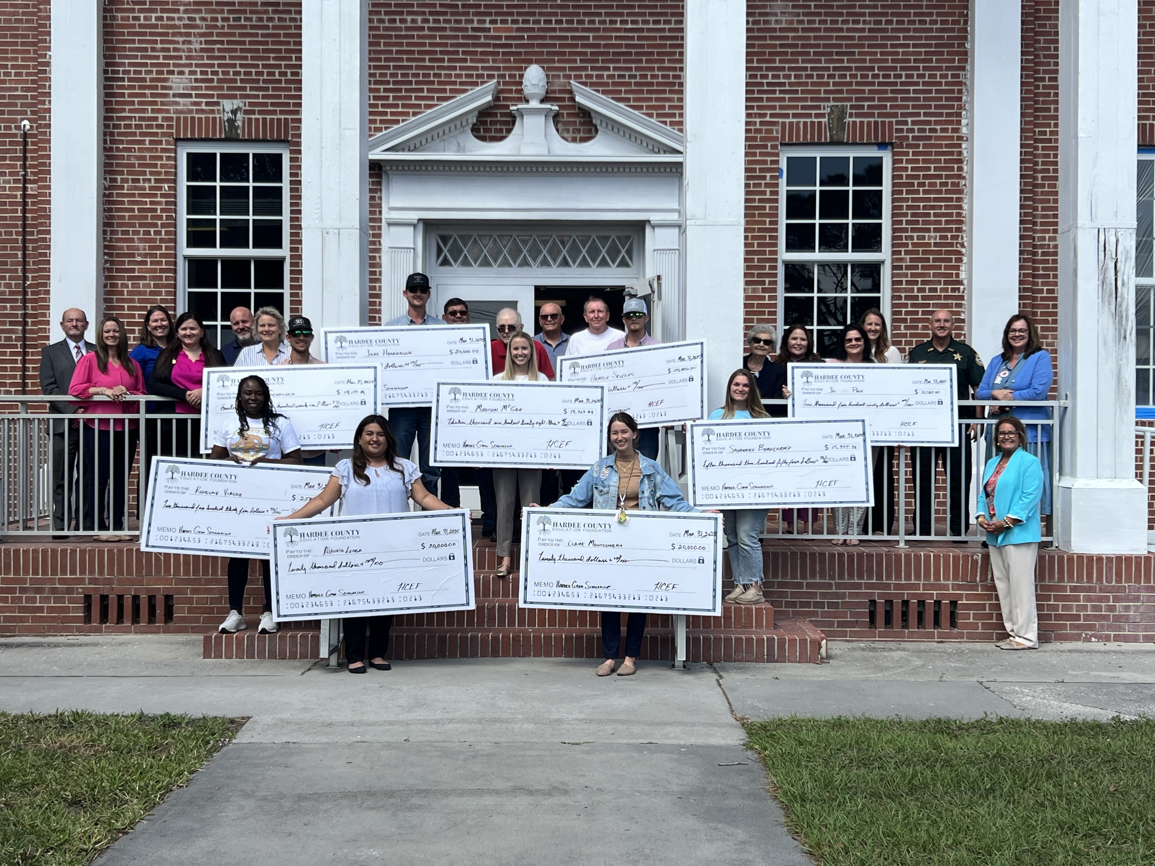 a group of people holding oversized checks for scholarships