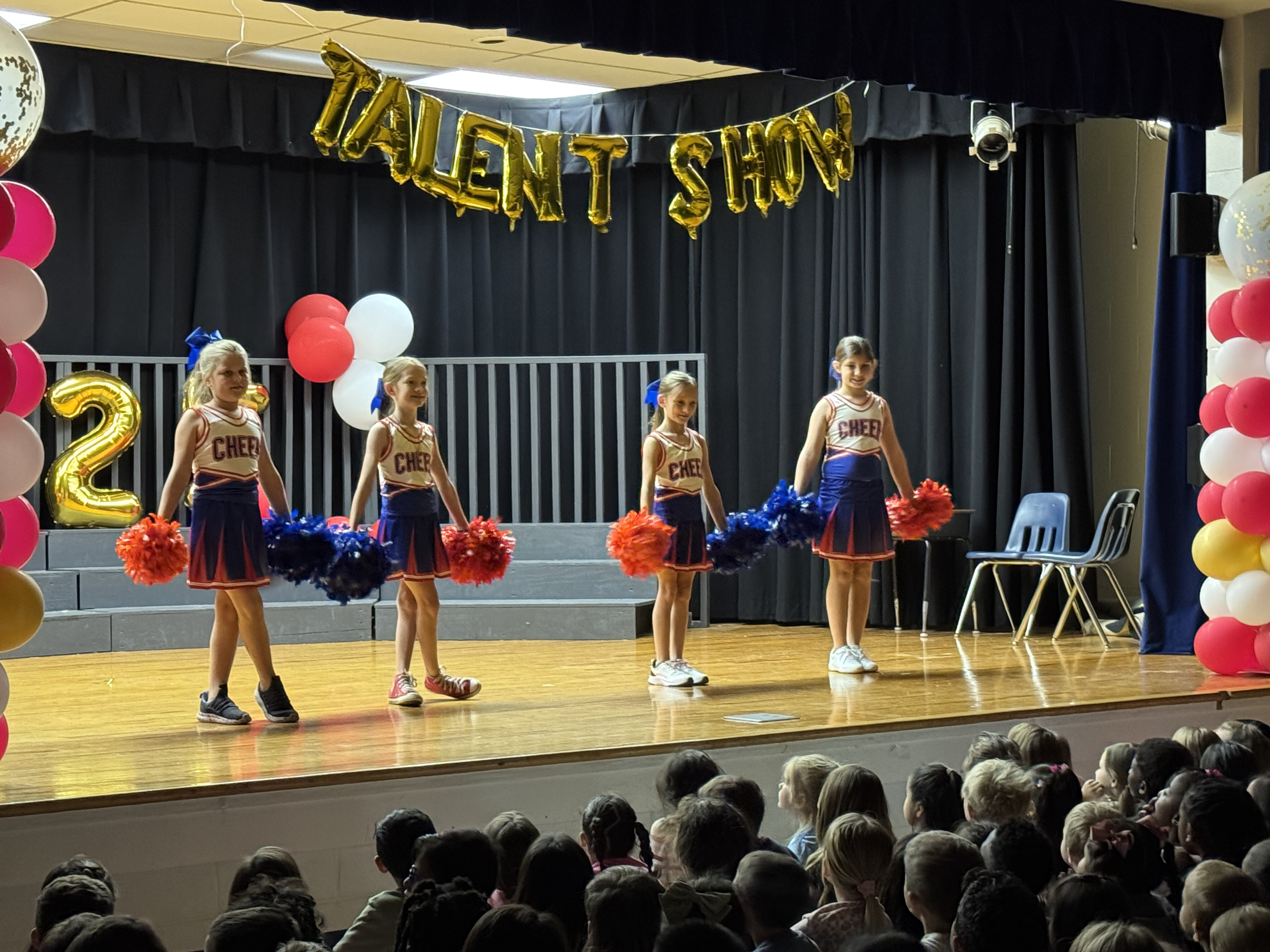 cheerleaders with pom poms on a stage for a talent show