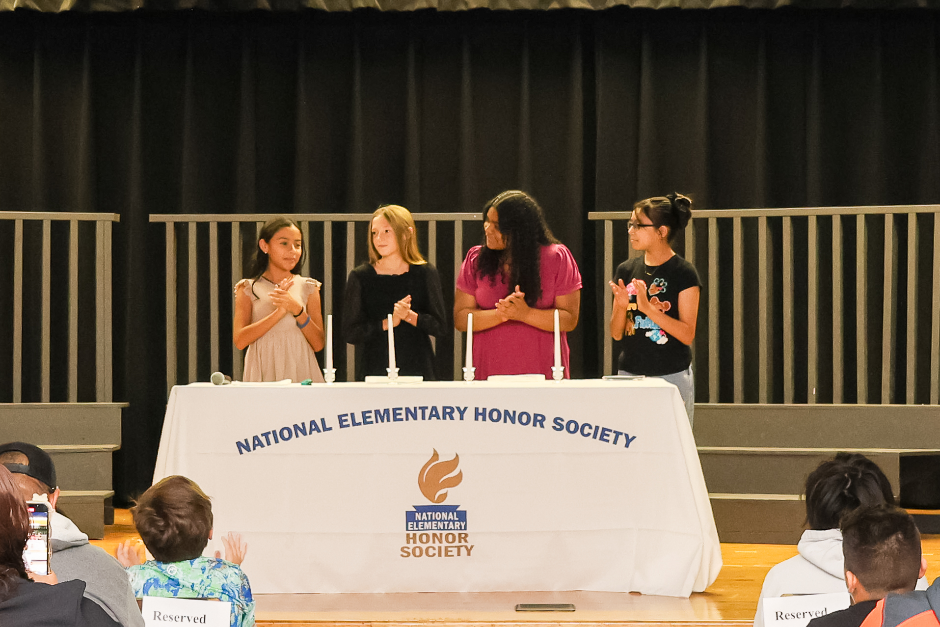 four students with candles at the national elementary honor society induction