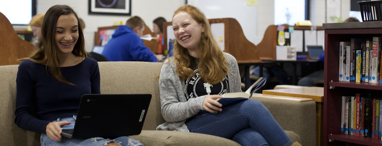 Two girls laughing in the library