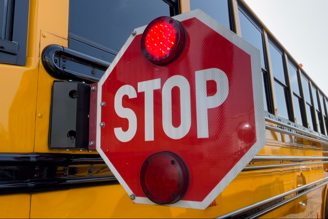 Photo of yellow school bus with stop sign out. The sign is lit up red.
