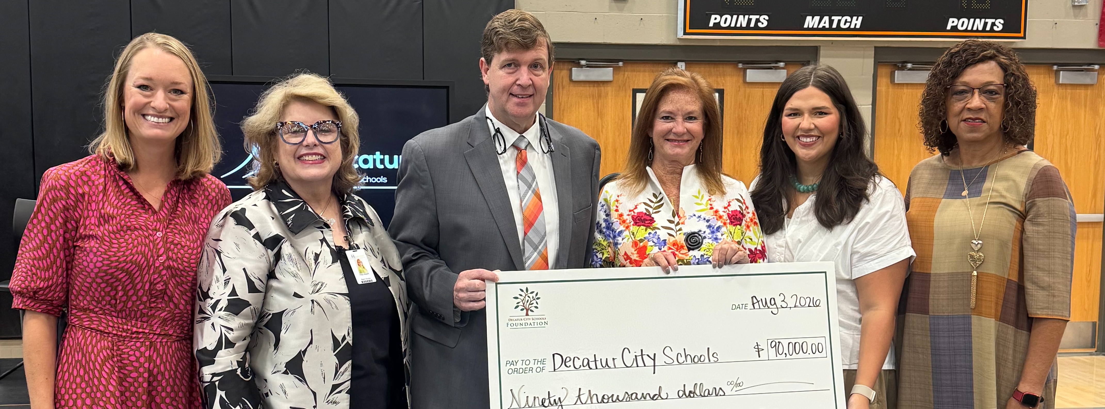 Representative Terri Collins stands beside Decatur City Schools admin during a check presentation.