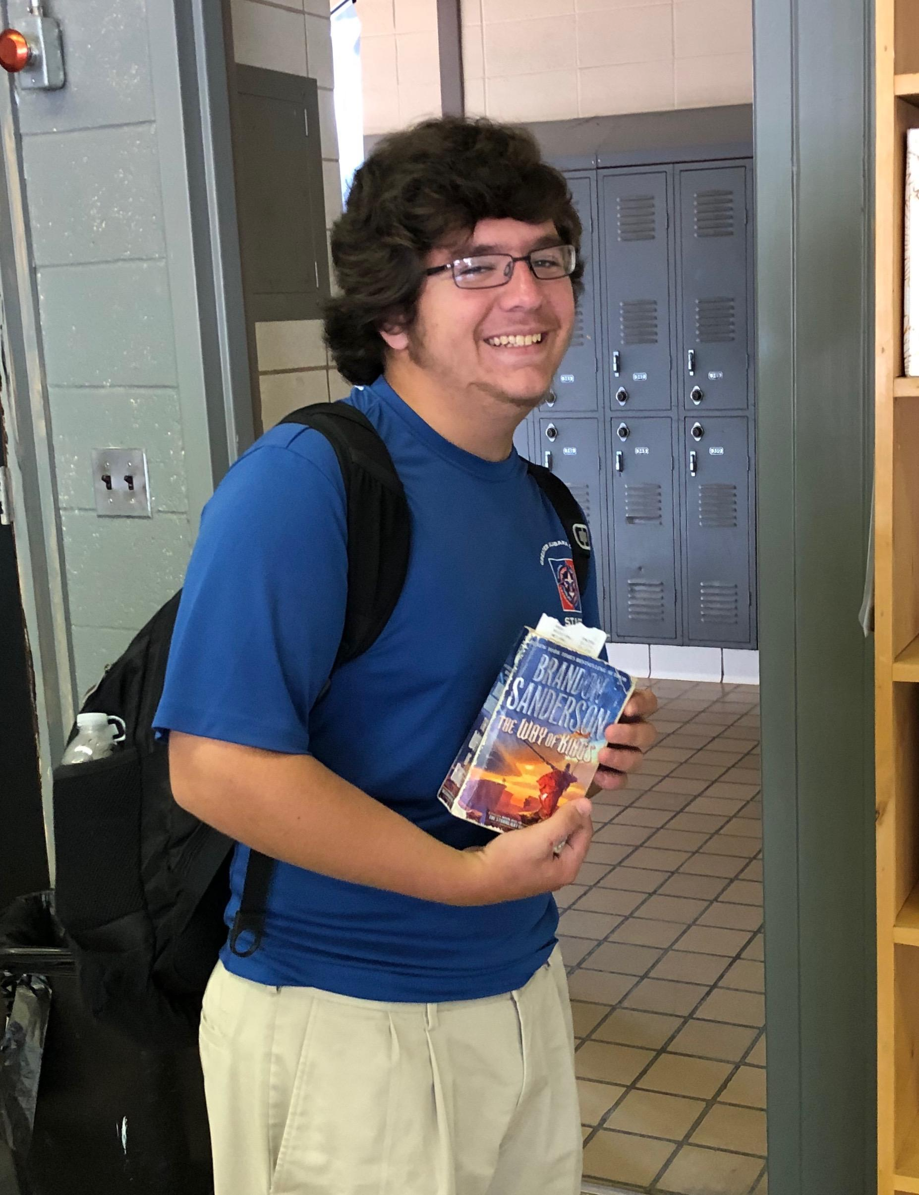 Student smiling for picture holding Brandon Sanderson the way of kings book