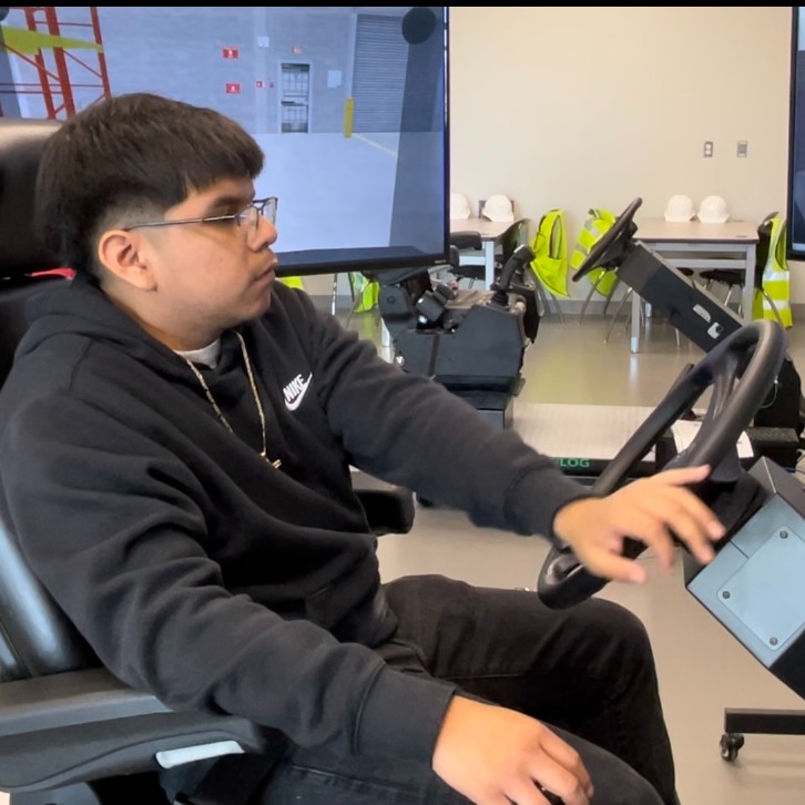 student practices driving heavy equipment using a high tech simulator