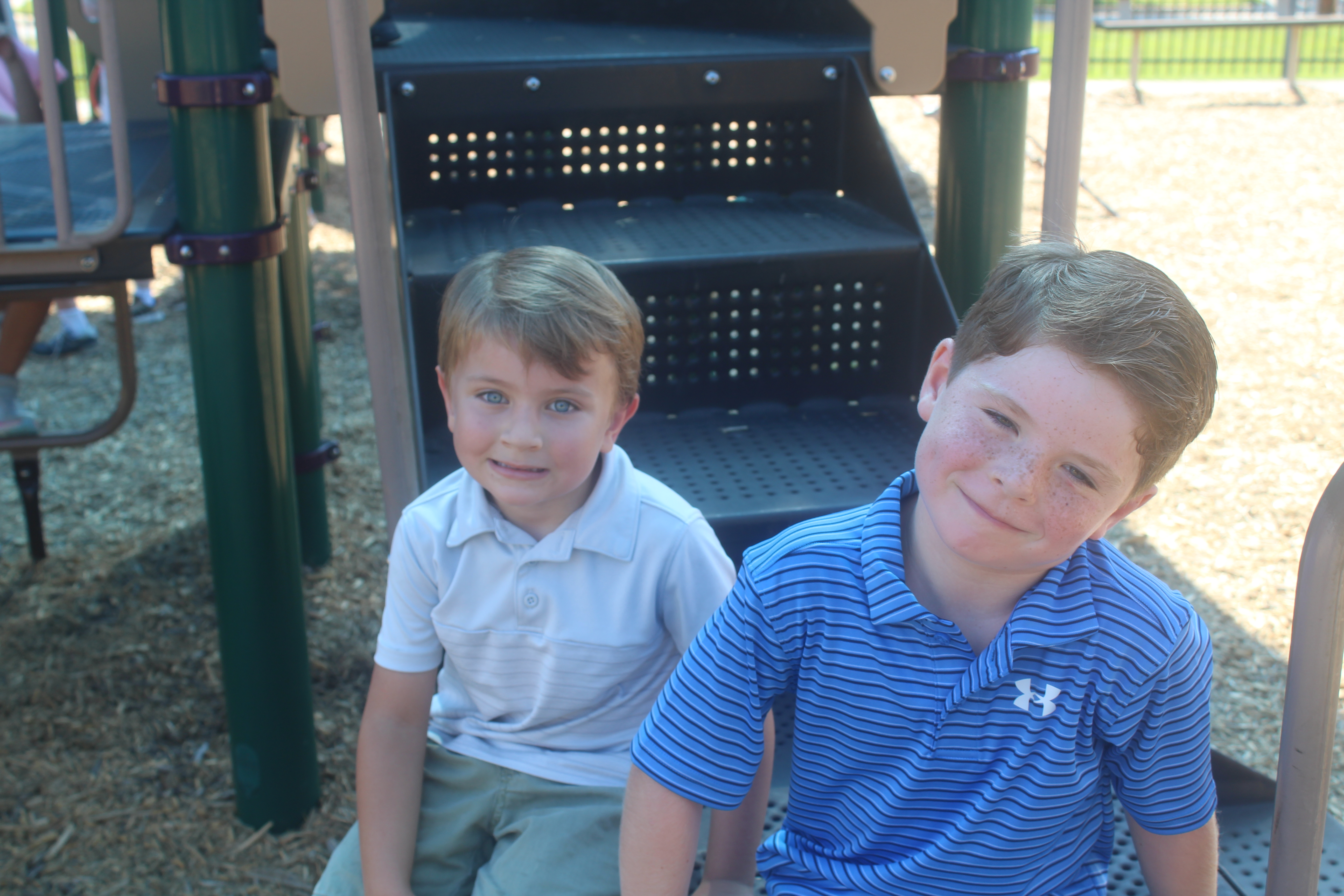 Two small boys sit on playground equipment
