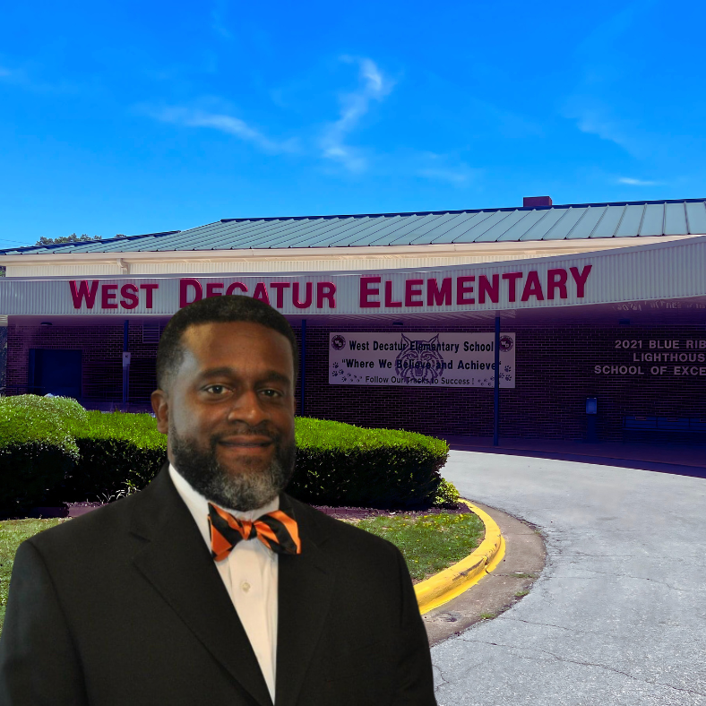 Assistant Principal Dr. Casey Lewis in front of the sign at West Decatur Elementary School