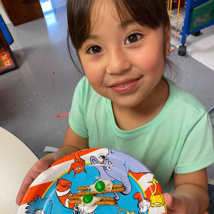 Elementary aged girl smiles with cat in the hat plate