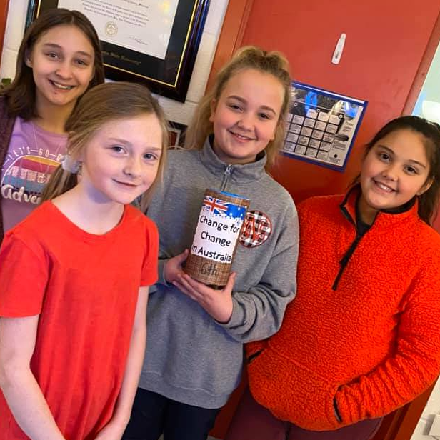 Girls pose with "Change for change in Australia" collection bucket