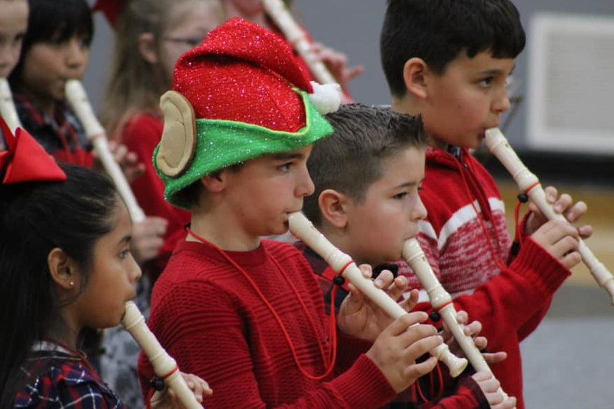 Student play recorders at Christmas concerts in holiday outfits