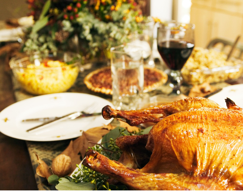Image of cooked turkey, plates, pie, and Thanksgiving floral centerpiece.