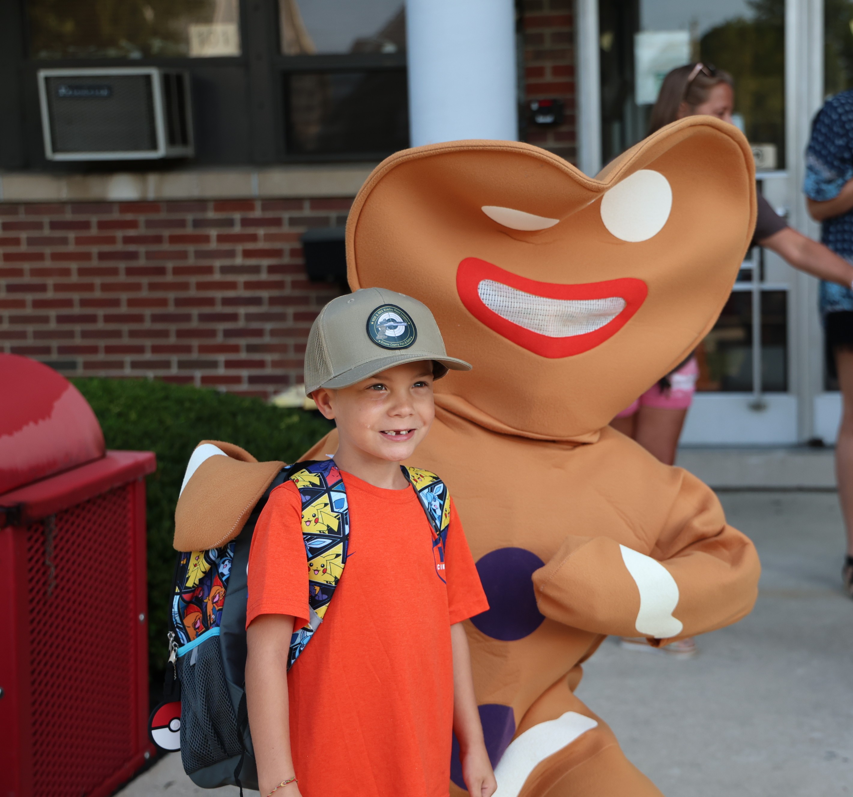 A little boy stands with the Gingerbread man on his way into school.