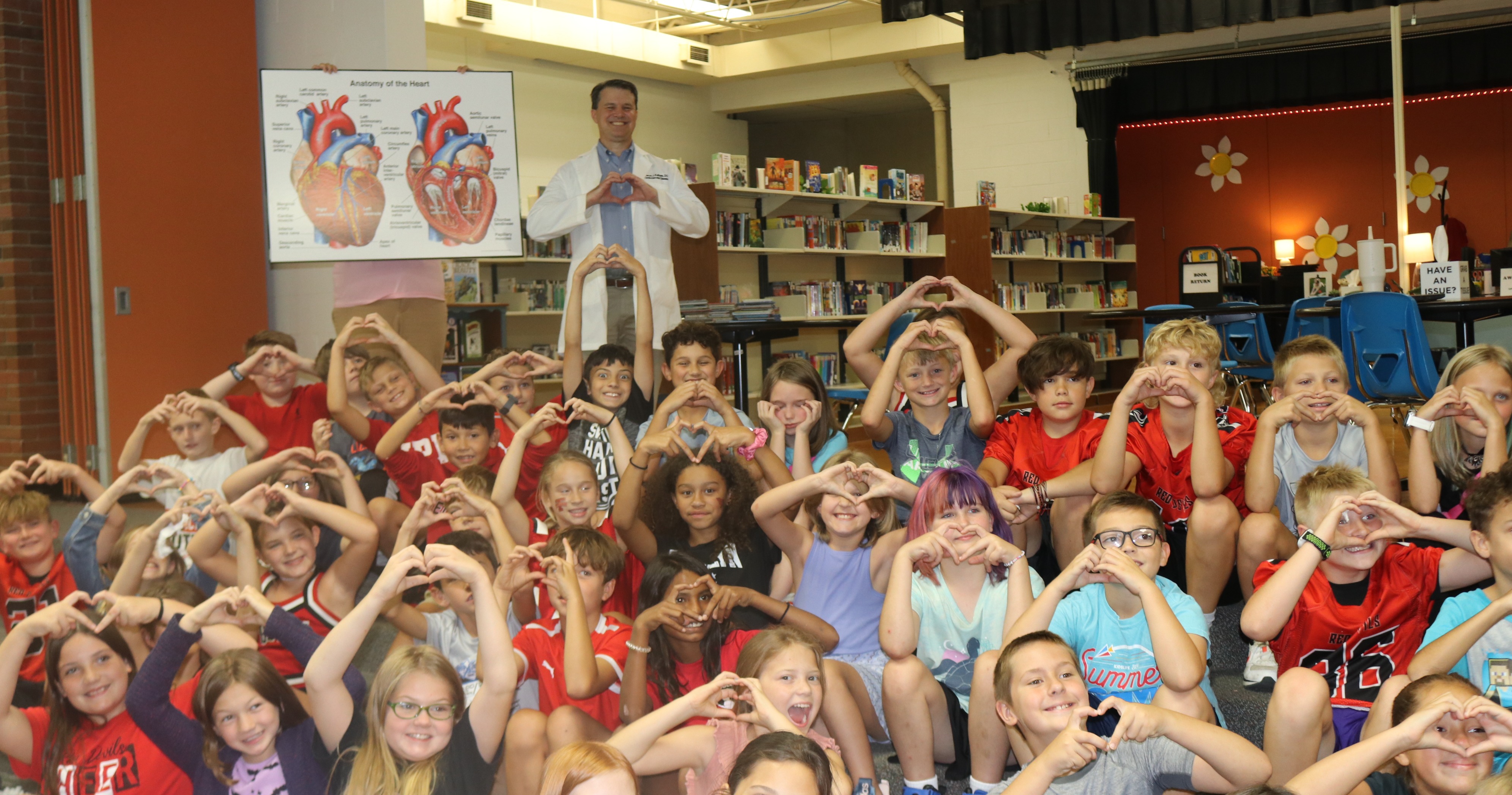 Students making a heart with guest speaker