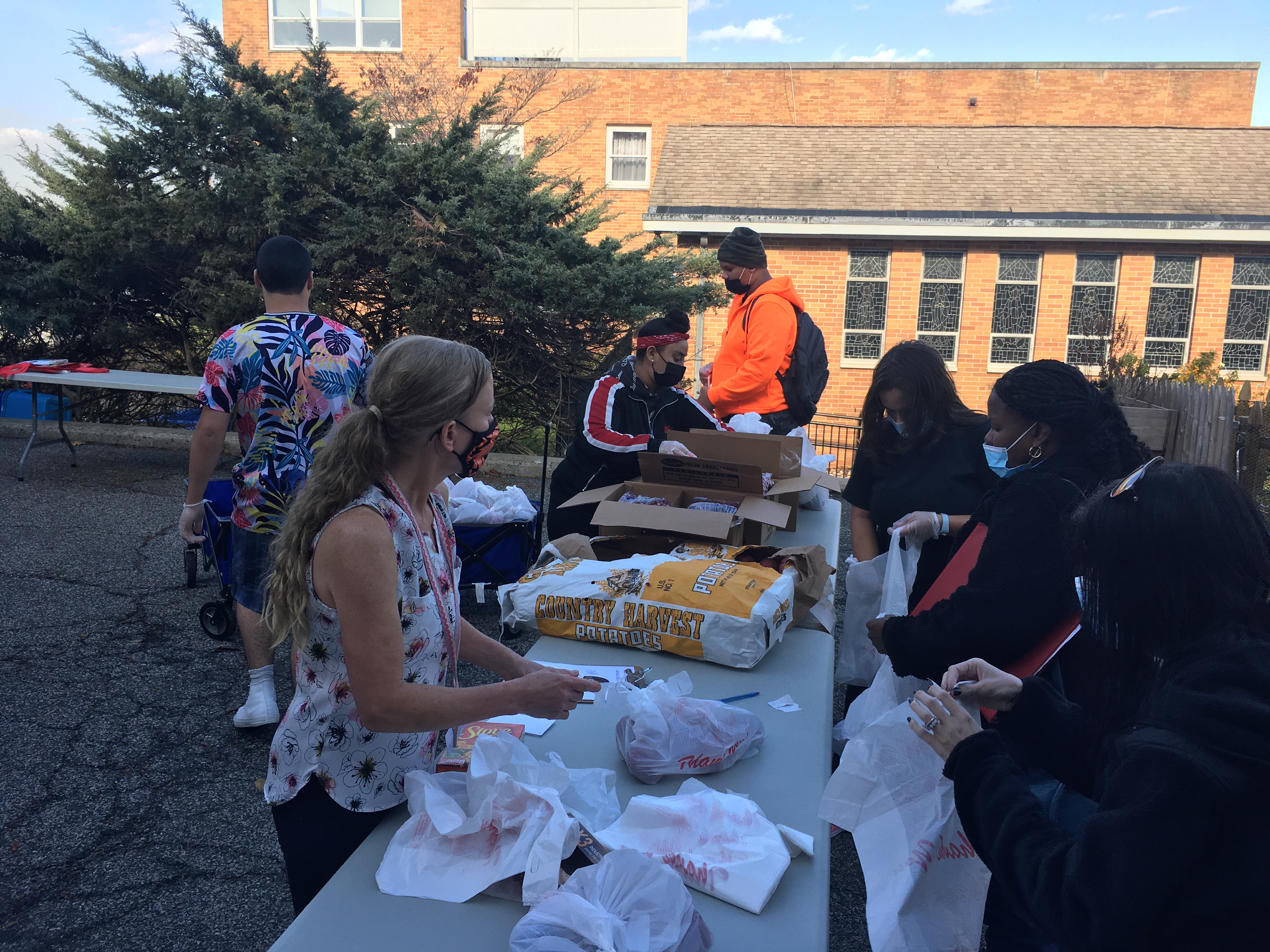 Staff and students are outside at the food pantry bagging food for distribution