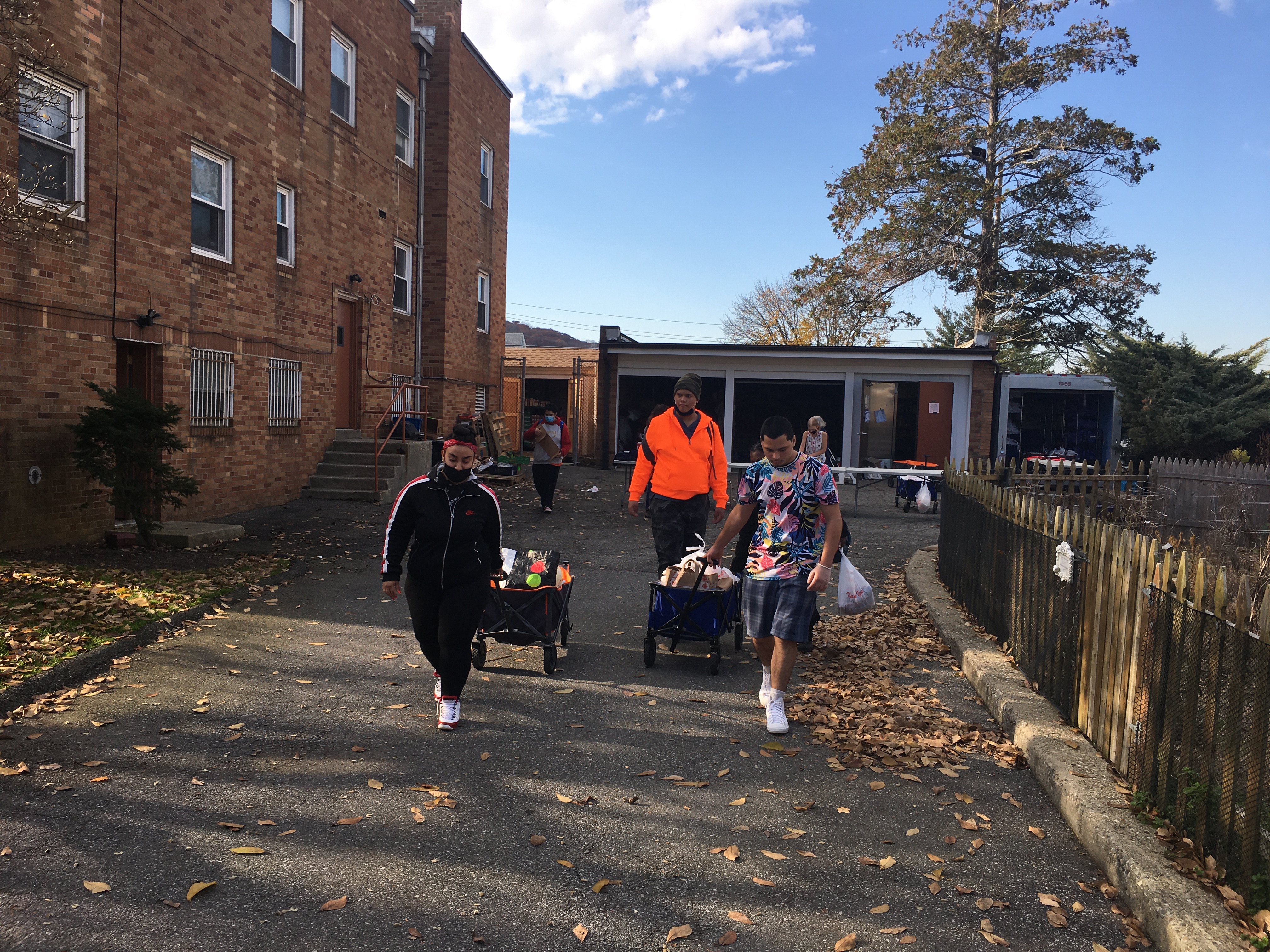 Students pull carts of bagged food from the food pantry towards the bus