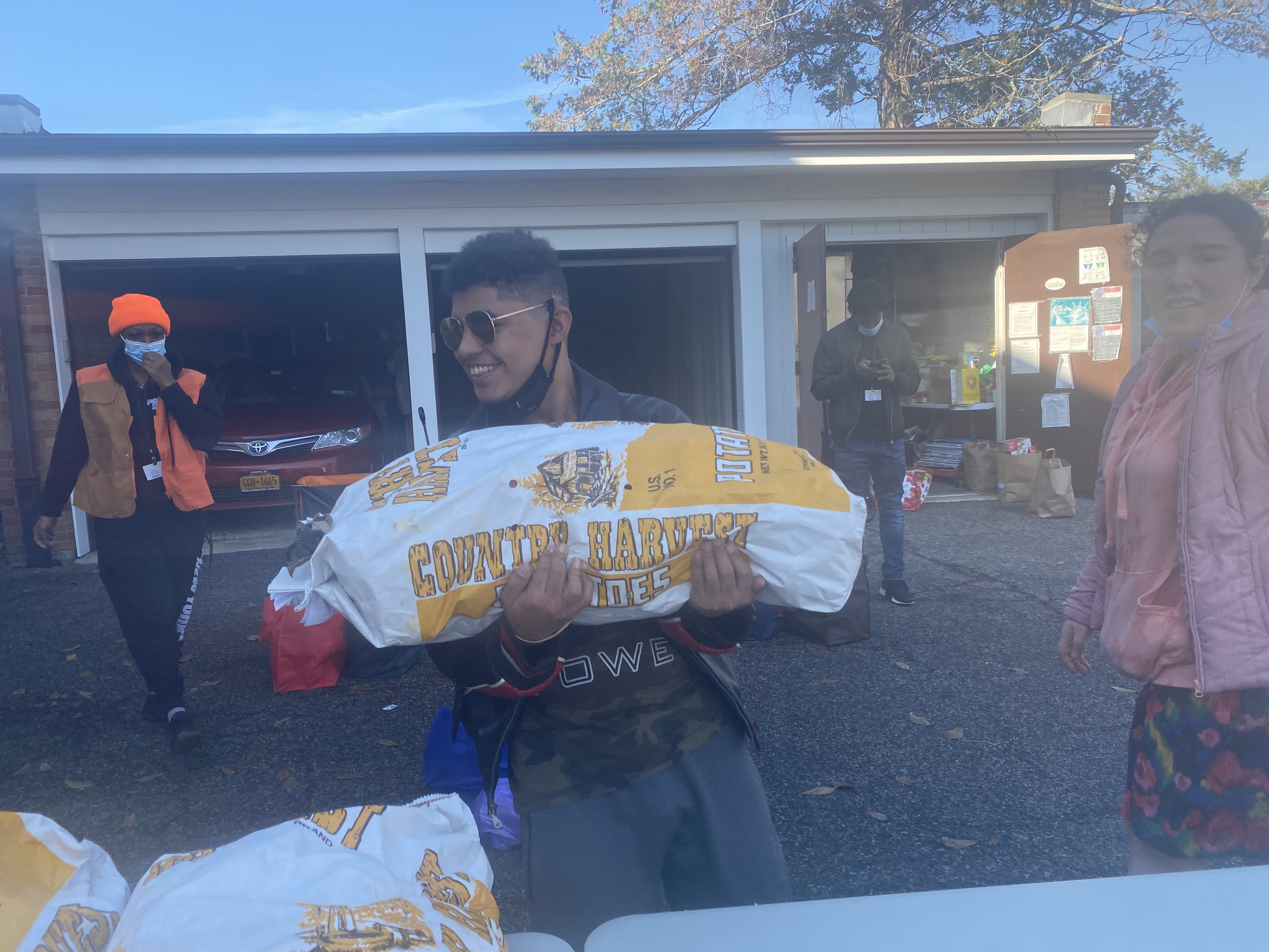 A student holds a large bag of potatoes at the food pantry