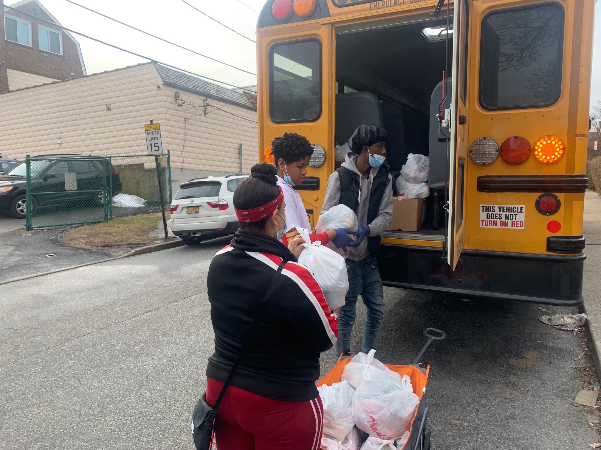Students help each other place all the bagged food inside the bus for transportation from the food pantry