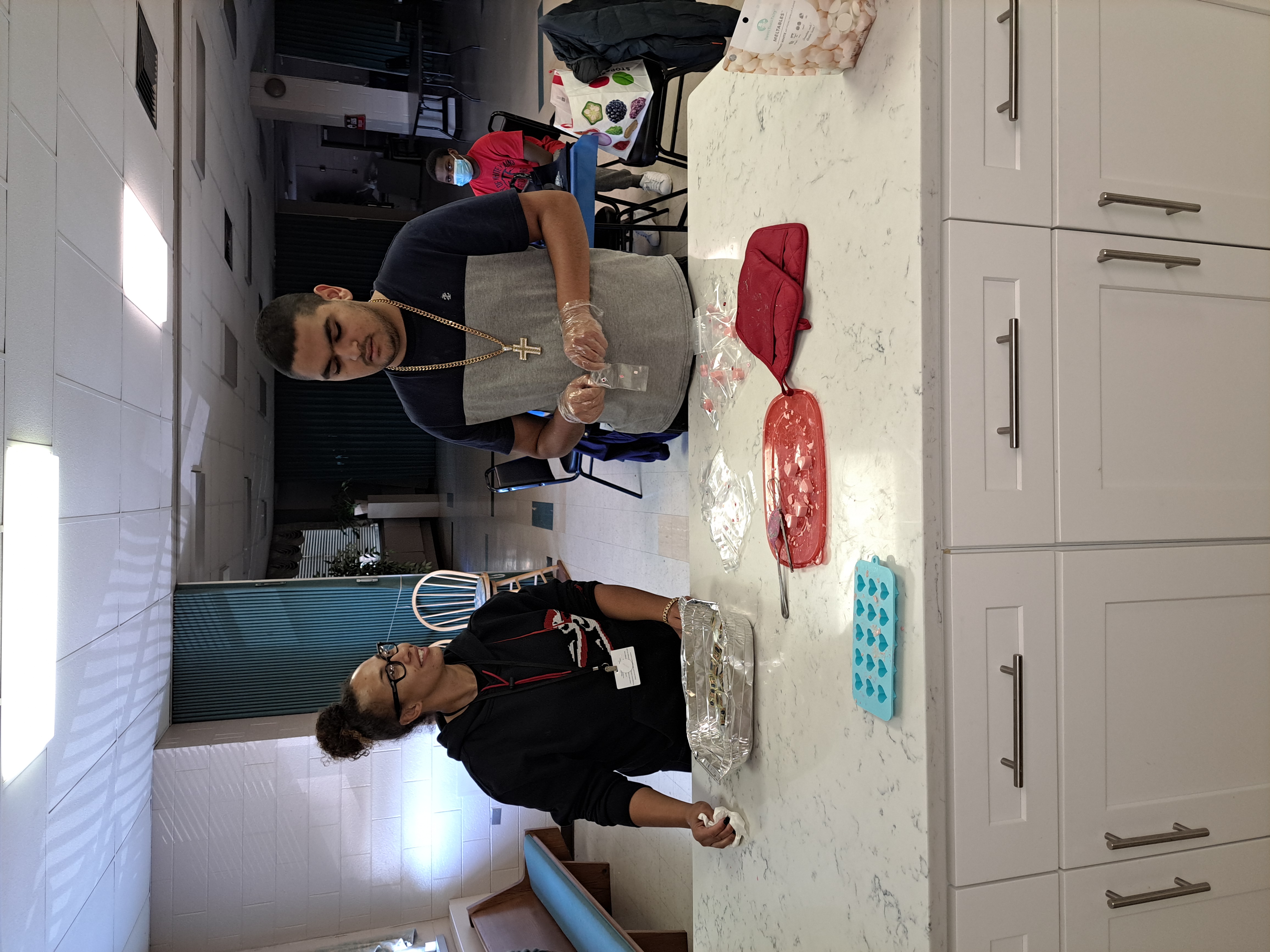 A staff member and a student stand at a kitchen counter preparing food