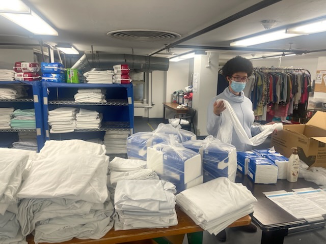 A student folds towels at the table inside a laundry room